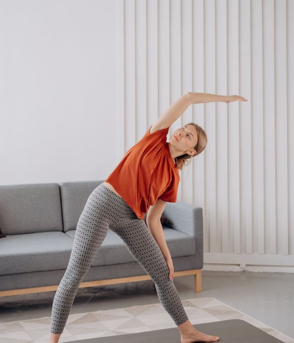 Woman practicing a gentle stretching pose in a bright, calm room.